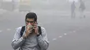 Seorang pria India berbicara menggunakan ponsel sambil menutup mulut saat kabut asap menyelimuti New Delhi, Rabu (8/11). Asosiasi Medis India mengumumkan kondisi darurat kesehatan setelah kabut asap tebal menutupi kota tersebut. (DOMINIQUE FAGET/AFP)
