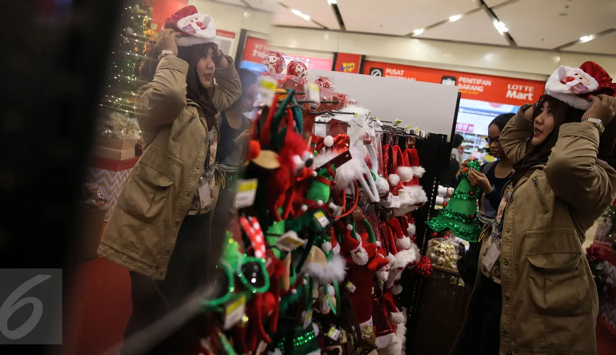 Pengunjung mencoba beberapa pernak-pernik natal yang dijual di Mall Gandaria City, Jakarta, Rabu (9/12/2015). Jelang perayaan hari raya umat Kristen, berbagai pernak-pernik dan hiasan rumah bertema Natal kini mulai marak. (Liputan6.com/Faizal Fanani)