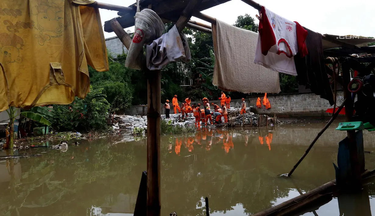 Pasukan oranye memperbaiki tanggul di wilayah Jati Padang, Jakarta, Kamis (30/11). Banjir yang terjadi tersebut akibat tanggul darurat di Kali Pulo jebol karena genangan air yang cukup deras dan membanjiri permukiman sekitar. (Liputan6.com/Johan Tallo)