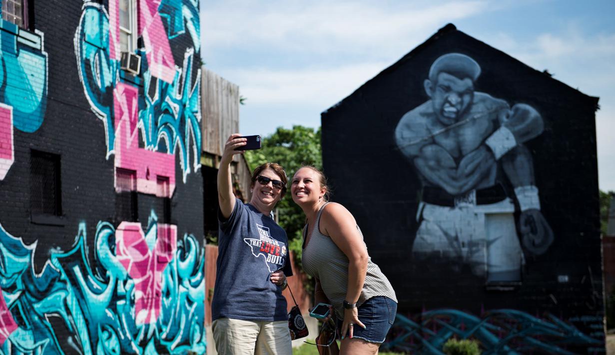 Warga berfoto di depan mural Muhammad Ali di Louisville, Kentucky, AS, (10/6/2016). (AFP/Brendan Smialowski)
