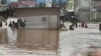 Di tengah banjir, warga Riau berupaya memindahkan rumah mereka.