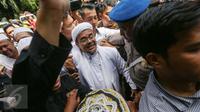 Imam Besar FPI, Habib Rizieq Shihab berusaha melewati kerumunan massa untuk memasuki gedung Dit Reskrimsus Polda Metro Jaya, Jakarta, Senin (23/1). Massa bertakbir dan melantunkan shalawat menyambut kedatangan Habib Rizieq. (Liputan6.com/Faizal Fanani)