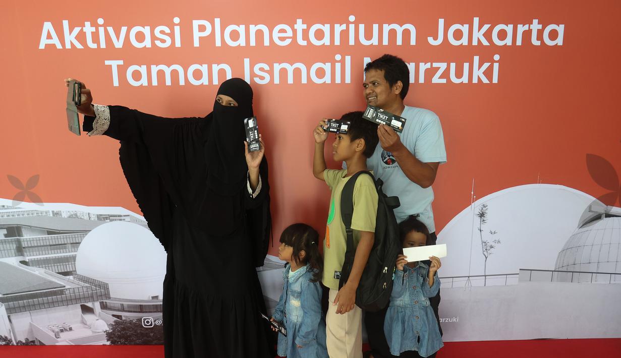 Pengunjung berswafoto sebelum memasuki area Planetarium di Taman Ismail Marzuki, Jakarta, Kamis (25/12/2025). Planetarium Taman Ismail Marzuki (TIM) akhirnya dibuka kembali. Planetarium Taman Ismail Marzuki (TIM) akhirnya dibuka kembali. (Kapanlagi.com/Budy Santoso)