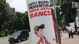 Pejalan kaki melintas di sisi media sosialisasi pelaksanaan Pemilu Serentak 2019 di depan kantor Kemenkominfo jalan Medan Merdeka Barat, Jakarta, Selasa (26/2). KPU menargetkan tingkat pemilih mencapai 77,5 persen. (Liputan6.com/Helmi Fithriansyah)