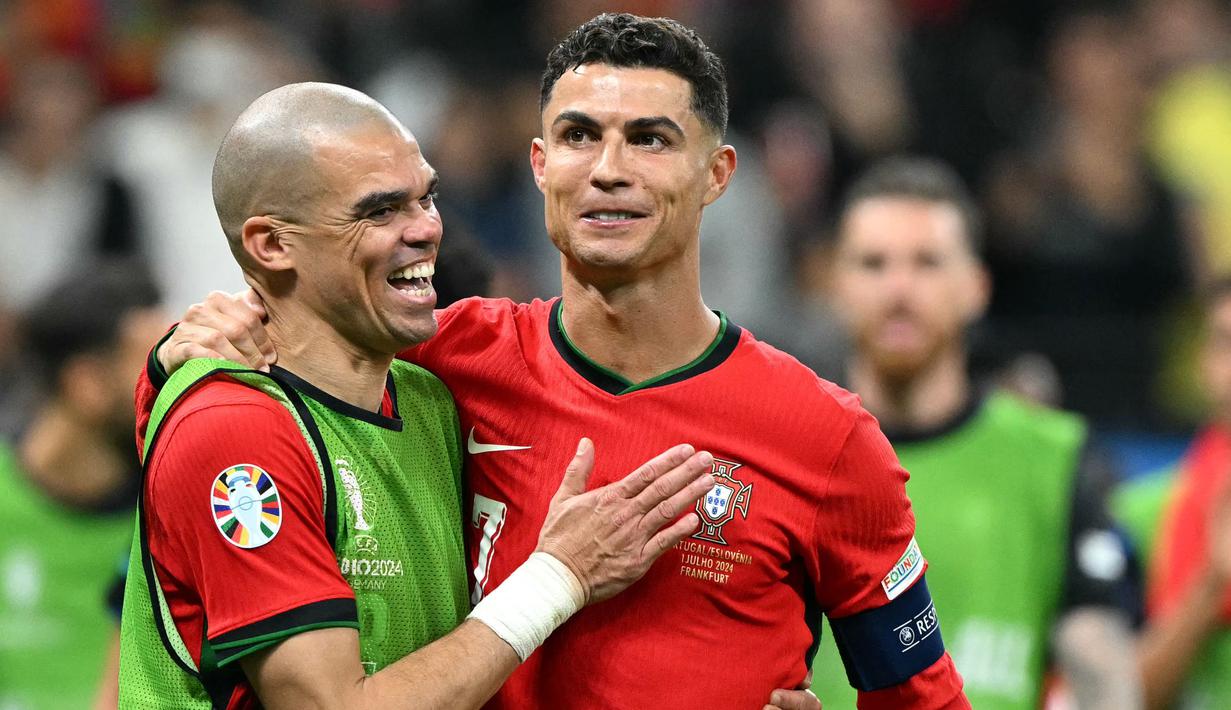 Pemain Portugal, Crsitiano Ronaldo, bersama Pepe tertawa saat timnya berhasil menaklukkan Slovenia pada babak 16 besar Euro 2024 di Frankfurt Arena, Selasa (2/7/2024). Selecao das Quinas menang adu penalti dan lolos ke perempat final. (AFP/Patricia De Melo Moreira)