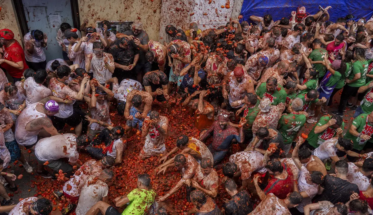 Orang-orang yang bersuka ria saling melempar tomat selama pesta pertarungan tomat tahunan "Tomatina", di desa Bunol dekat Valencia, Spanyol, Rabu (28/8/2024).  (AP Photo/Alberto Saiz)