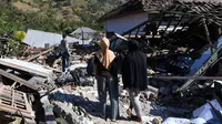 Dua wanita melihat warga menyelamatkan sisa-sisa puing dari rumah yang rusak di Menggala, Lombok Utara, Rabu (8/8). Warga terdampak gempa Lombok mulai mengamankan barang berharga karena kuatir dijarah pihak tidak bertanggung jawab. (AFP/ADEK BERRY)