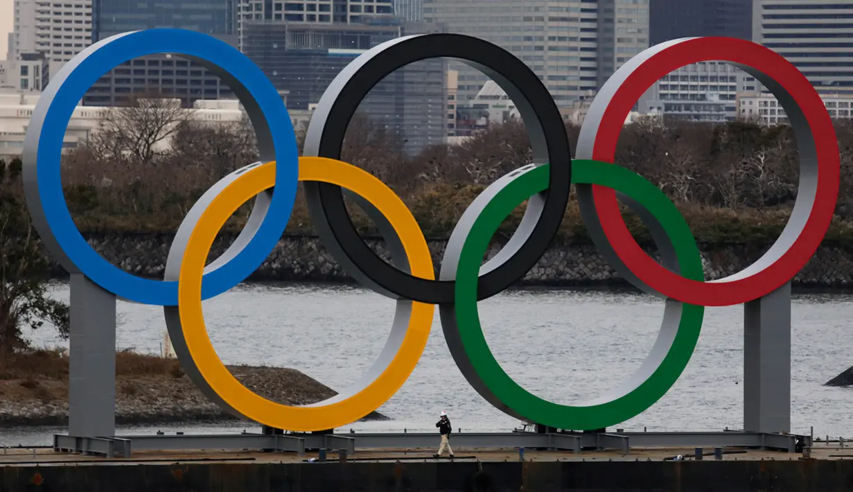Pekerja berjalan di kapal tongkang yang membawa Cincin Olimpiade di Distrik Odaiba, Tokyo, Jepang, Jumat (17/1/2020). Cincin Olimpiade dengan tinggi 15,3 meter dan panjang 32,6 meter tersebut akan berada di sana hingga Olimpiade 2020 berakhir. (AP Photo/Jae C. Hong)