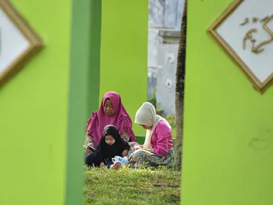 Warga berdoa saat melakukan ziarah di Kuburan Massal Ulee Lheue selama peringatan 14 tahun tsunami Aceh di Banda Aceh, Rabu (26/12). Sejumlah warga mengenang keluarga yang meninggal akibat bencana tsunami di Aceh 14 tahun silam. (Chaideer MAHYUDDIN / AFP)