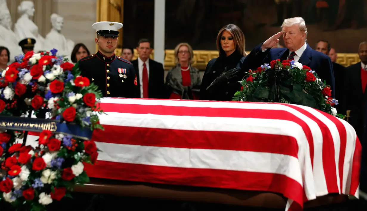 Presiden AS Donald Trump dan Melania Trump memberikan penghormatan terakhir kepada George HW Bush di Gedung Capitol, Washington, Senin (3/12). Jenazah Presiden ke-41 AS itu disemayamkan di Rotunda Capitol Hill selama beberapa hari. (AP/Jacquelyn Martin)