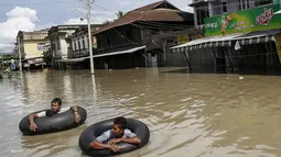 Warga menggunakan ban untuk melintasi jalanan yang terendam banjir di kawasan Kalay, Sagaing, Myanmar, Minggu (2/8/2015). Setidaknya 21 orang tewas akibat banjir yang melanda empat wilayah di Myanmar. (REUTERS/Soe Zeya Tun)