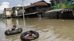 Warga menggunakan ban untuk melintasi jalanan yang terendam banjir di kawasan Kalay, Sagaing, Myanmar, Minggu (2/8/2015). Setidaknya 21 orang tewas akibat banjir yang melanda empat wilayah di Myanmar. (REUTERS/Soe Zeya Tun)
