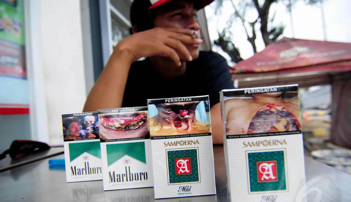 Seorang perokok tampak menunjukan bungkus rokok yang telah berganti peringatan bergambar di minimarket, Jakarta, Selasa (24/6/14). (Liputan6.com/Faizal Fanani)