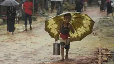 Seorang anak pengungsi Rohingya berjalan membawa rantang selama musim hujan di kamp pengungsi Kutupalong, Ukhia (12/9/2019). Kamp ini adalah salah satu dari dua kamp pengungsi yang dikelola pemerintah di Cox's Bazar, kamp yang satunya lagi adalah kamp pengungsi Nayapara. (AFP Photo/Munir Uz Zaman)