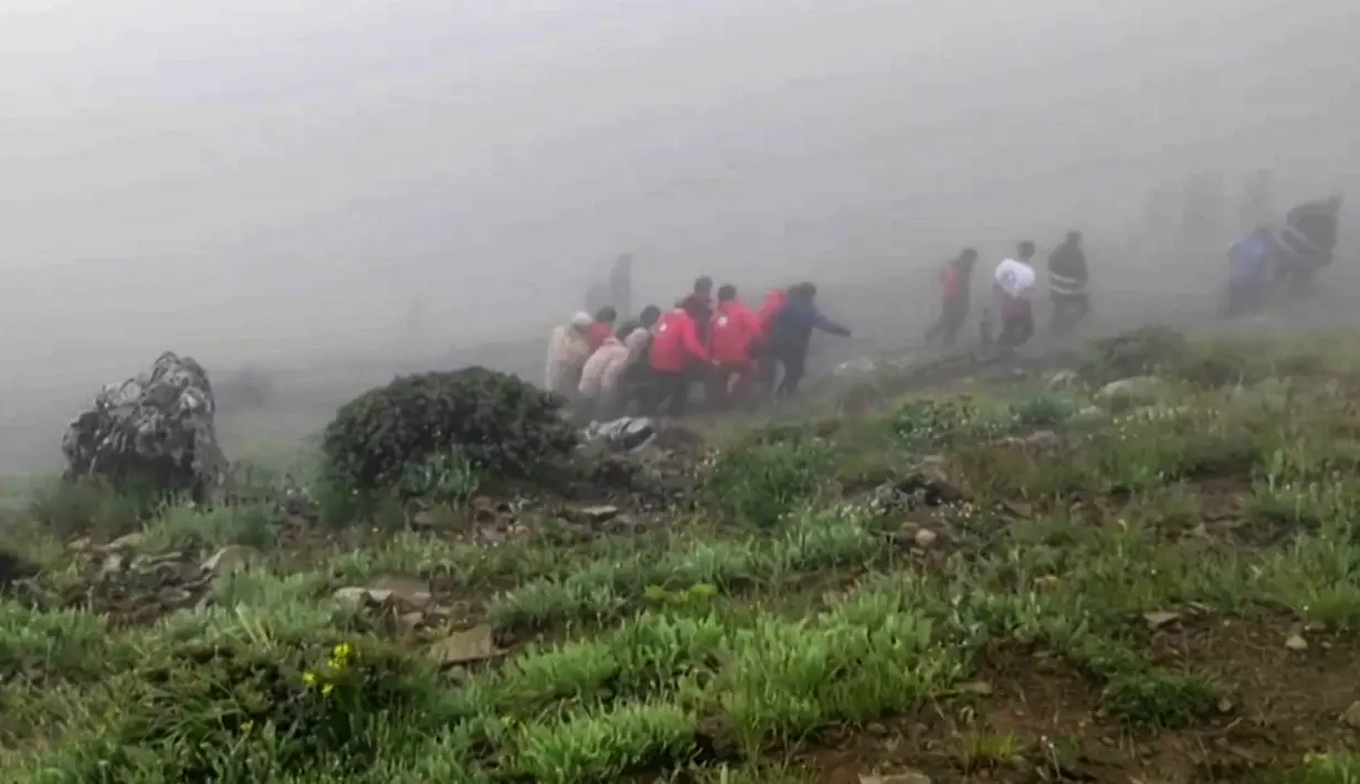 Gambar ini diambil dari rekaman video selebaran yang dirilis oleh Bulan Sabit Merah Iran pada 20 Mei 2024 yang menunjukkan tim penyelamat menemukan jenazah di lokasi jatuhnya helikopter Presiden Ebrahim Raisi di daerah pegunungan yang diselimuti kabut di barat laut Iran. (Iranian Red Crescent / AFP)