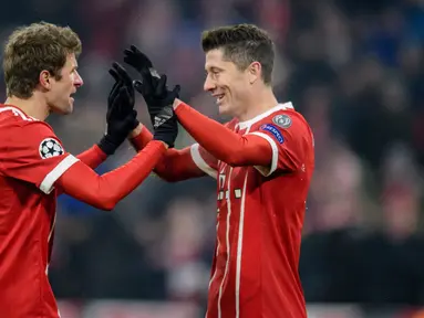 Pemain Bayern Munchen, Robert Lewandowski berselebrasi dengan Thomas Mueller usai mencetak gol ke gawang Besiktas pada pertandingan pertama babak 16 besar Liga Champions di Allianz Arena, Selasa (20/2). Bayern menang telak 5-0. (Matthias Balk/dpa via AP)