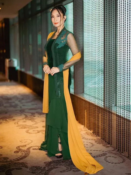 Happy Salma tampil dengan kebaya hijau model kutu baru yang lebih modern dengan detail sedikit bordiran di bagian atas dan lengan transparannya. Dipadukan selendang kuning panjang dan bawahan rok panjang ruffle warna hijau. [@happysalma]
