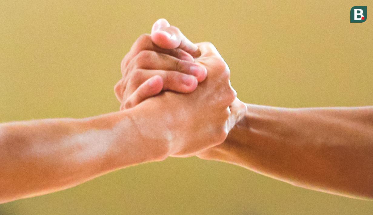 Tangan pebasket Global Nusantara School, Roadericoz Marchander (kanan) saat membangunkan rekannya, Kevin Ryan Djoe saat laga 16 besar DBL 2023/2024 Seri Jakarta Utara dan Jakarta Pusat antara SMAN 45 Jakarta melawan Global Multimedia School di GOR Cempaka Putih, Jakarta Pusat, Minggu (13/08/2023). (Bola.com/Bagaskara Lazuardi)