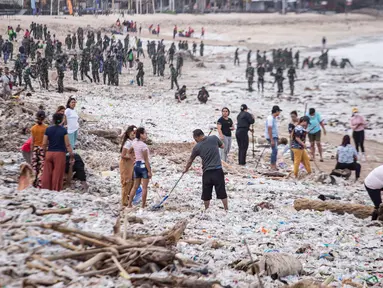 Para pekerja dan warga membersihkan ceceran dan tumpukan sampah plastik yang terdampar di Pantai Jimbaran, Bali, pada Selasa 10 Maret 2026. Pantai Jimbaran, Bali, kembali dipenuhi sampah kiriman. (Lana Priatna/AFP)