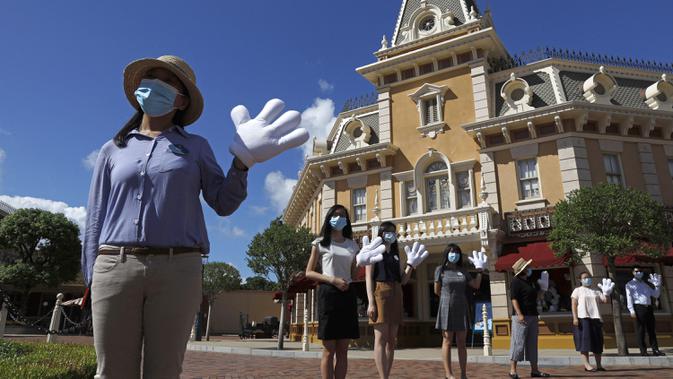 Pegawai yang mengenakan masker untuk mencegah penyebaran COVID-19 menyambut pengunjung di Disneyland Hong Kong, Kamis (18/6/2020). Disneyland Hong Kong kembali beroperasi pada 18 Juni 2020 dengan menerapkan sejumlah protokol kesehatan baru. (AP Photo/Kin Cheung)