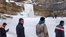 Sejumlah pengunjung melihat air terjun Mirusha yang membeku di Lapceve, Kosovo (9/1). Cuaca bersuhu mencapai minus 20 derajat celcius membuat Air Terjun Mirusha dan kolam membeku. (AFP Photo/Armend Nimani)