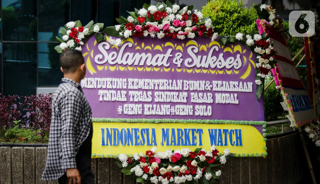 Seorang pria melintas di depan karangan bunga dukungan di halaman Kementerian BUMN Jakarta, Kamis (16/1/2020). Kantor Menteri BUMN Erick Thohir kembali mendapat kiriman bunga berupa dukungan untuk menyelesaikan masalah PT Asuransi Jiwasraya (Persero). (Liputan6.com/Faizal Fanani)