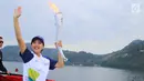 Artis Olivia Zalianty membawa obor Asian Games 2018 berkeliling Danau Toba di Sumatra Utara, Rabu (1/8). Obor Asian Games itu akan di bawa berlayar dengan kapal hias di Danau Toba dan bersepeda menuju pantai bebas Danau Toba. (Liputan6.com/Reza Perdana)