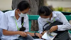 Dua siswi mengenakan masker membaca buku di sebuah sekolah di Phnom Penh (28/1/2020). Kementerian kesehatan Kamboja melaporkan kasus pertama virus korona mematikan di negara itu pada 27 Januari. (TANG CHHIN SOTHY/AFP)
