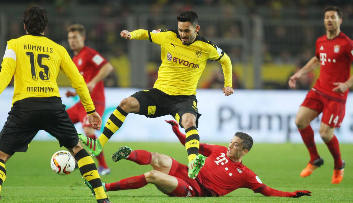 Pemain Bayern Munchen, Robert Lewandowski terjatuh saat berduel dengan pemain Dortmund Mats Hummels (kiri) dan Ilkay Gundogan pada lanjutan Bundesliga 2015-2016 di Stadion Signal Iduna Park ,Dortmund, Minggu (5/3/2016) dini hari WIB. (EPA/Ina Fassbender)