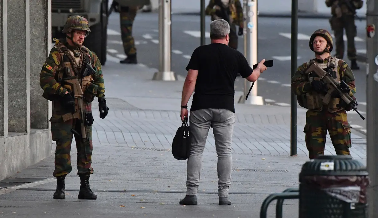 Tentara Belgia berbincang dengan seorang pria di luar Central Station usai sebuah teror ledakan yang terjadi di Brussels, Belgia (20/6). Media Belgia melaporkan bahwa ledakan terjadi di stasiun kereta api Gare Centrale. (AP Photo/Geert Vanden Wijngaert)