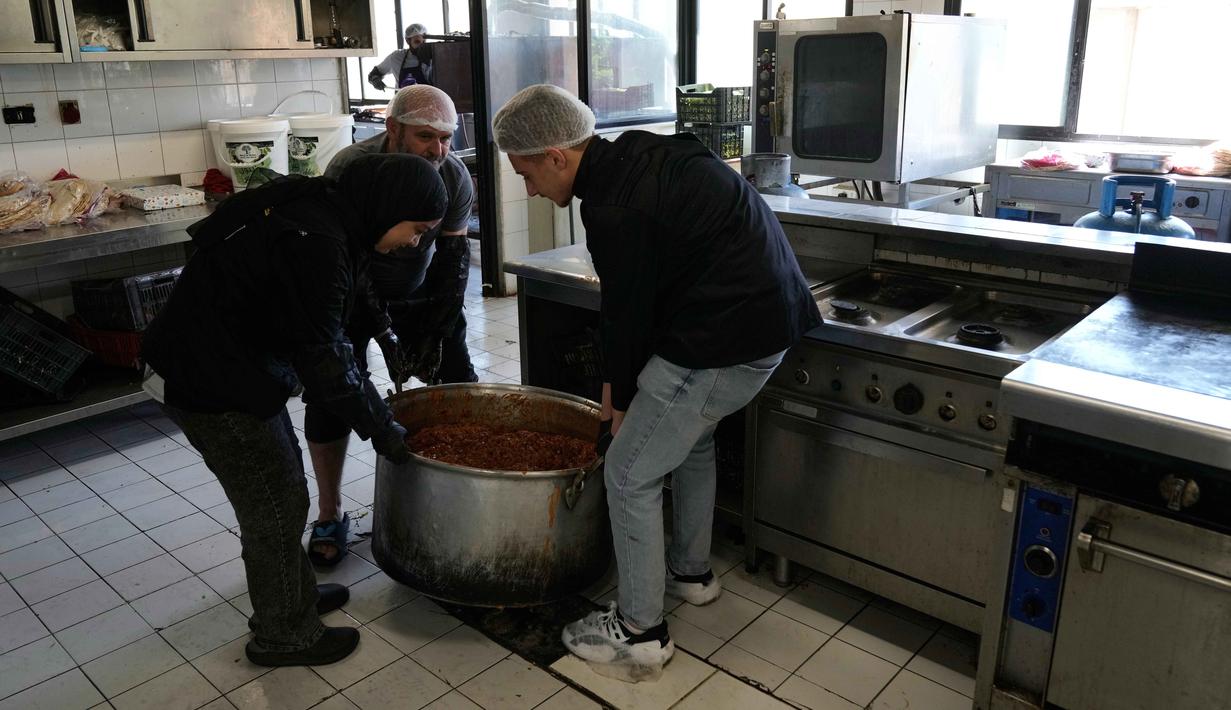 Gelombang pengungsian ini terjadi setelah peringatan evakuasi dan serangan udara intensif di wilayah selatan dan Beirut. Tampak dalam foto, para sukarelawan memasak makanan untuk para pengungsi yang menghindari serangan udara Israel di Lebanon selatan dan Dahiyeh, di Institut Teknik Bir Hassan yang telah diubah menjadi tempat penampungan, Beirut, Rabu 11 Maret 2026. (AP Photo/Bilal Hussein)
