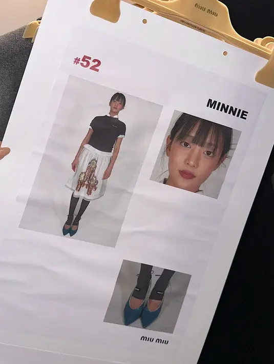 Penyanyi itu mengenakan rok putih rancangan desainer yang dipadukan dengan kaos Miu Miu yang berkelas dan kemeja putih. Penampilan perdana Minnie di panggung peragaan busana dilengkapi dengan kaus kaki setinggi lutut dan sepatu hak tinggi berwarna biru kehijauan.  [Dok/Miu Miu dan @min.nicha].