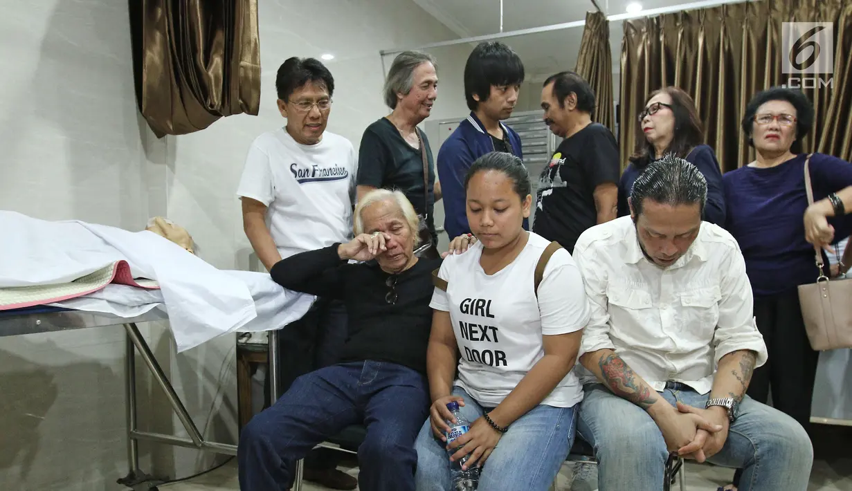 Anak Benny Panjaitan, Dino dan Victorian duduk dekat jenazah sang ayah di rumah duka RS Dharmais, Jakarta, Selasa (24/10). Pentolan band Panbers itu meninggal di usia 70 tahun akibat penyakit stroke yang lama dideritanya. (Liputan6.com/Herman Zakharia)