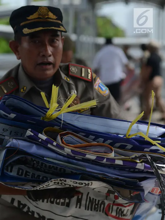 Petugas Satpol PP membawa APK Pemilu 2019 di Kawasan Jalan Pemuda, Jakarta, Rabu (13/3). APK Pemilu 2019 yang terpasang pada JPO dibersihkan hal tersebut mengganggu dan melanggar aturan pemasangan dari komisi Pemilihan umum. (merdeka.com/Imam Buhori)