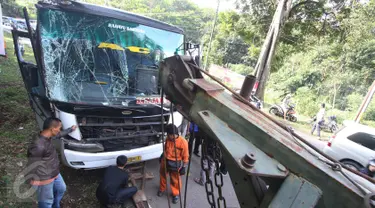 Petugas menggunakan mobil derek untuk mengevakuasi bus PO Merdeka yang menabrak pohon di jalur Lingkar, Jawa Barat, Sabtu (2/7). Kecelakaan terjadi karena rem bus bernopol Z 7829 T itu tidak berfungsi, alias blong. (Liputan6.com/Immanuel Antonius)