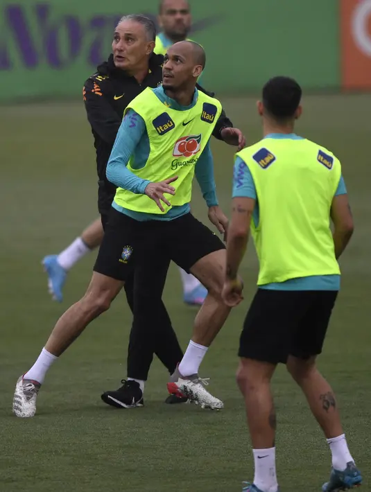 Pelatih Brasil Tite (kiri) dan gelandang Fabinho (tengah) mengambil bagian dalam sesi latihan di Granja Comary, Rio de Janeiro, Minggu (27/3/2022). Brasil akan menghadapi Bolivia dalam laga lanjutan Kualifikasi Piala Dunia 2022 zona Amerika Selatan pada Rabu, 30 Maret mendatang. (MAURO PIMENTEL/AFP)