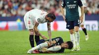 Pemain Sevilla, Sergio Ramos, berusaha membantu pemain Arsenal, Takehiro Tomiyasu, yang terjatuh pada laga Liga Champions di Stadion Ramon Sanchez Pizjuan, Rabu (25/10/2023). Berkat hasil ini, Arsenal kini berhak naik ke puncak klasemen Grup B dengan poin 6. Sementara itu, Sevilla menduduki posisi ketiga dengan perolehan poin 2. (AFP/Jorge Guerrero)