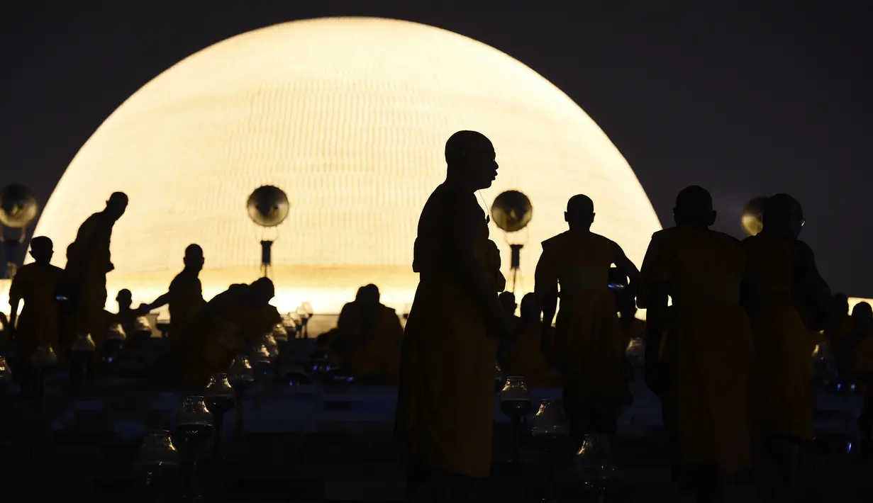 Sejumlah biksu bergegas mencari tempat duduk untuk melakukan ritual Makha Bucha Day di kuil Wat Dhammakaya, Bangkok, Thailand (11/2). Biasanya bulan Magha ini jatuh antara bulan Februari dan Maret. (AFP/Lillian Suwanrumpha)