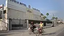Warga Palestina bersepeda melewati sebuah hotel di Gaza City, 17 September 2020. Lebih dari 500 tempat wisata di Gaza, termasuk hotel, restoran, gedung pernikahan, dan kafe, telah ditutup menyusul penerapan lockdown yang menyebabkan 7.000 pekerja menganggur sementara. (Xinhua/Rizek Abdeljawad)