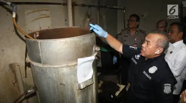 Petugas polisi dari Reskrimsus menunjukan drum tempat pembuatan ciu saat menggelar rilis di kawasan Pekojan, Tambora, Jakarta (3/5). Dari industri rumahan tersebut polisi menyita 22.000 liter bahan baku fermentasi ciu. (Liputan6.com/Arya Manggala)