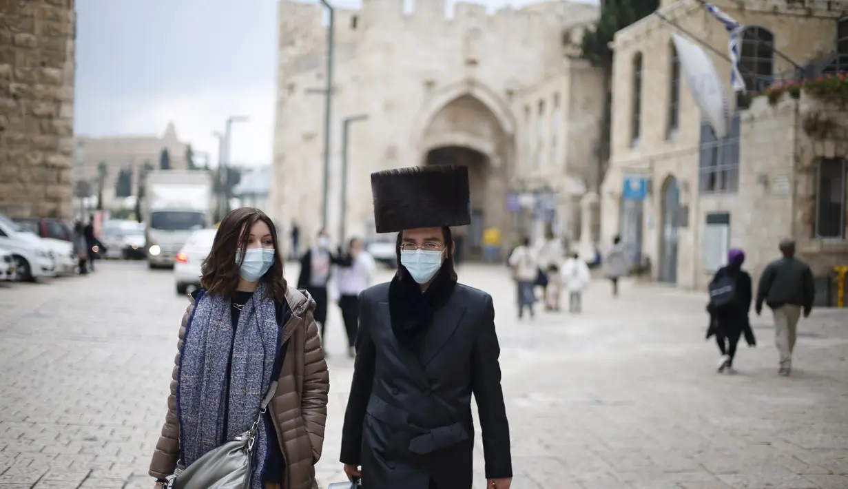 Wanita dan pria mengenakan masker berjalan di luar Kota Tua Yerusalem di tengah pandemi COVID-19 (25/11/2020). (Xinhua/Muammar Awad)