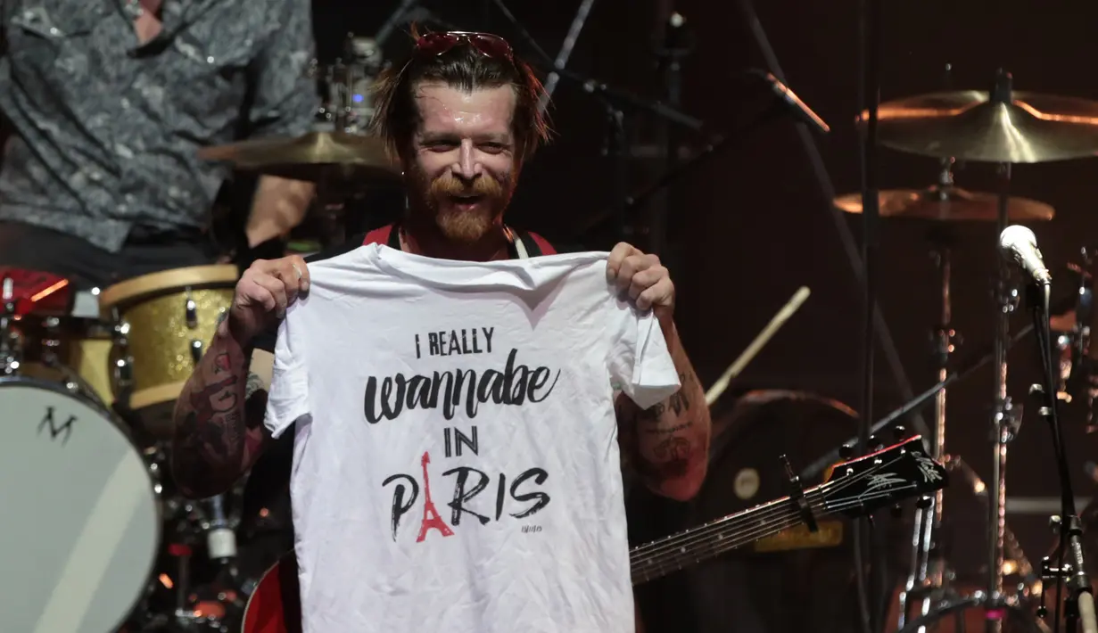 Jesse Hughes, vokalis grup rock Eagles of Death Metal, memperlihatkan kaos ke hadapan penggemarnya sebelum memulai konser perdana mereka setelah serangan Paris pada November 2015 lalu, di gedung teater Olympia, Paris, Selasa (16/2). (AFP PHOTO/Joel SAGET)