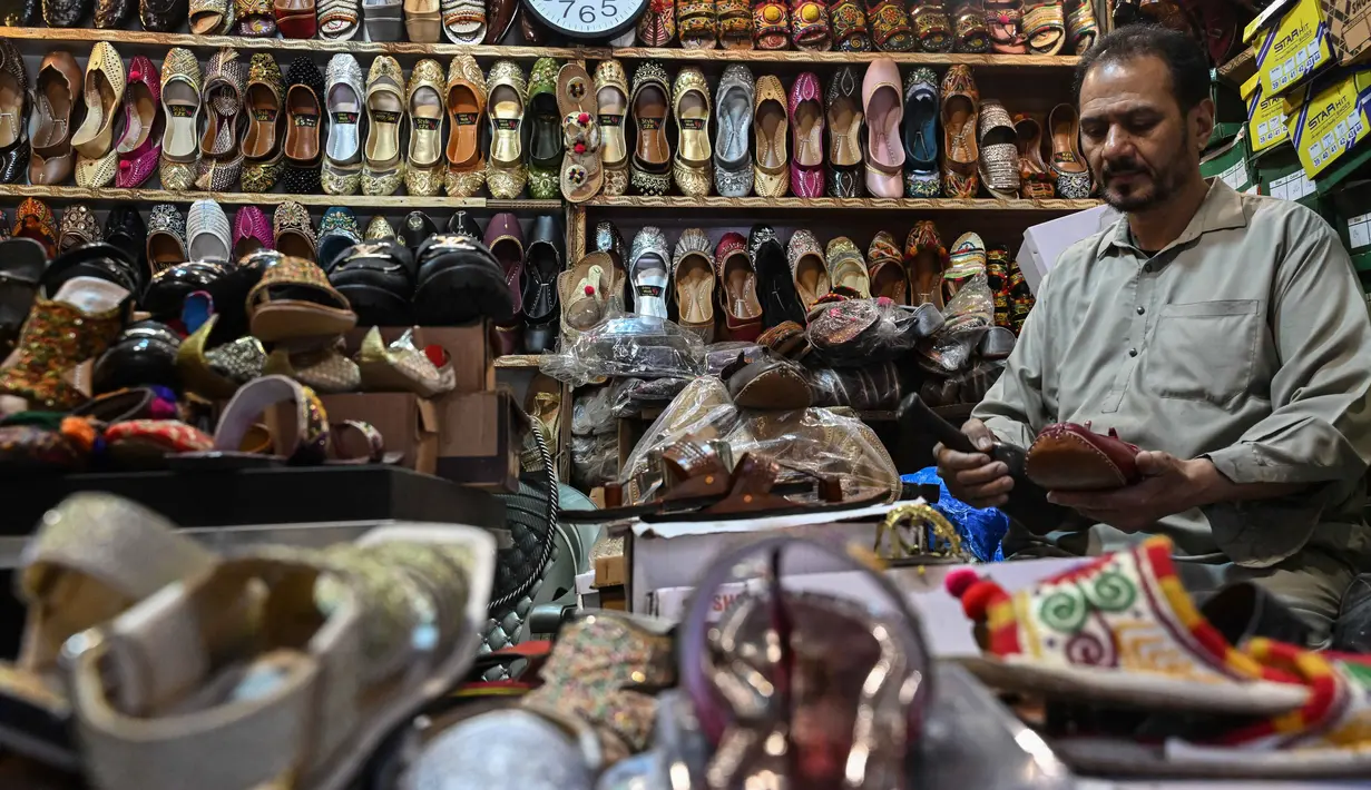 Sepatu datar ini dikenal karena keindahan sulaman benang, manik-manik, atau cermin yang rumit, menjadikannya pilihan utama untuk acara khusus, salah satunya perayaan Idul Fitri. Tampak dalam foto, aktivitas seorang pembuat sepatu membuat khussa, alas kaki tradisional, di sebuah bengkel menjelang perayaan Idul Fitri selama bulan suci Ramadan 1447 Hijriah di Lahore pada 14 Maret 2026. (Arif ALI/AFP)
