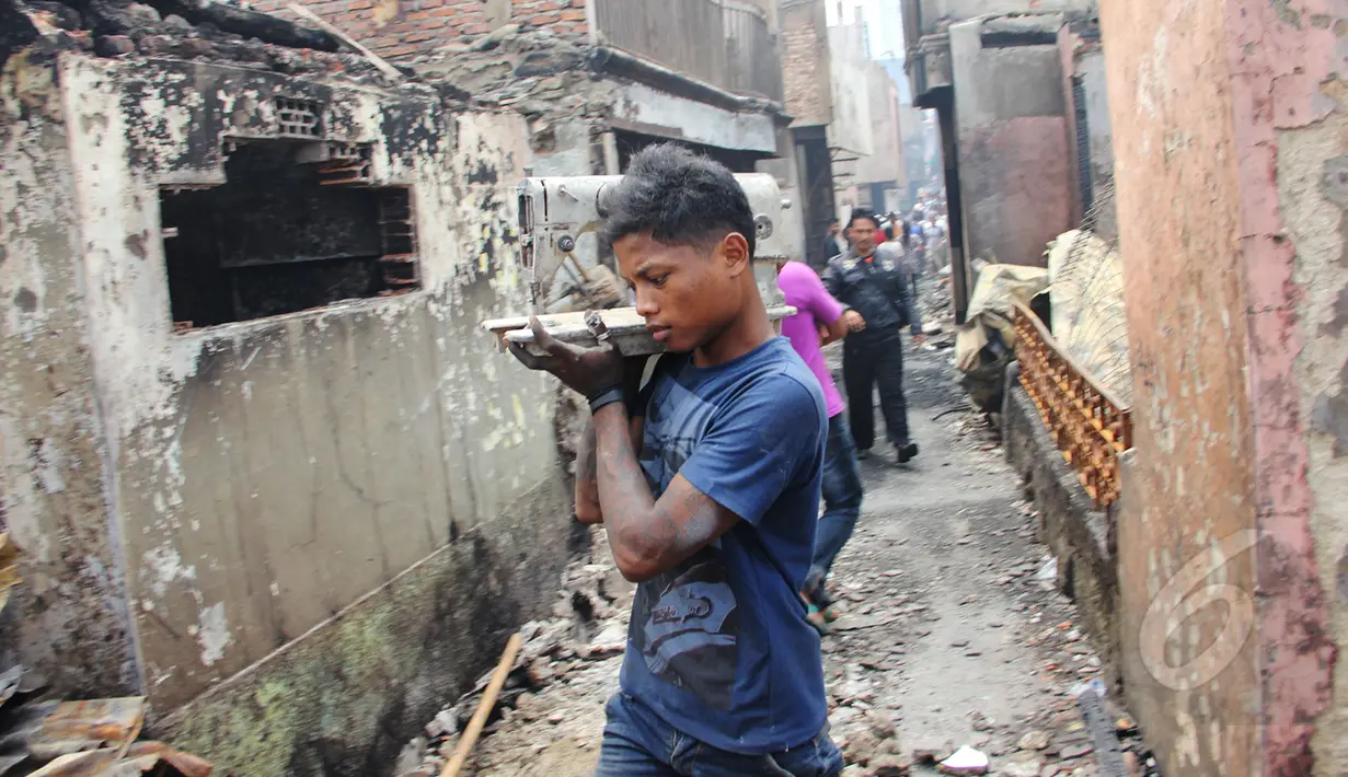 Seorang warga saat mengangkat barang miliknya usai kebakaran di kawasan Kebon Melati Tanah Abang, Jakarta, Jumat (6/3/2015). Kebakaran yang terjadi menyebabkan setidaknya2 RW dan 6 RT di kelurahan kebon melati terbakar. (Liputan6.com/Helmi Afandi)