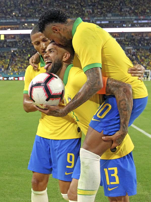 Penyerang Brasil, Neymar Jr mencium kepala bek Dani Alves saat berselebrasi mencetak gol ke gawang Kolombia selama laga uji coba di Hard Rock Stadium, Florida (7/9/2019). Gol neymar pada menit ke-58 ini menjadi penyelamat Brasil. (David Santiago/Miami Herald via AP)