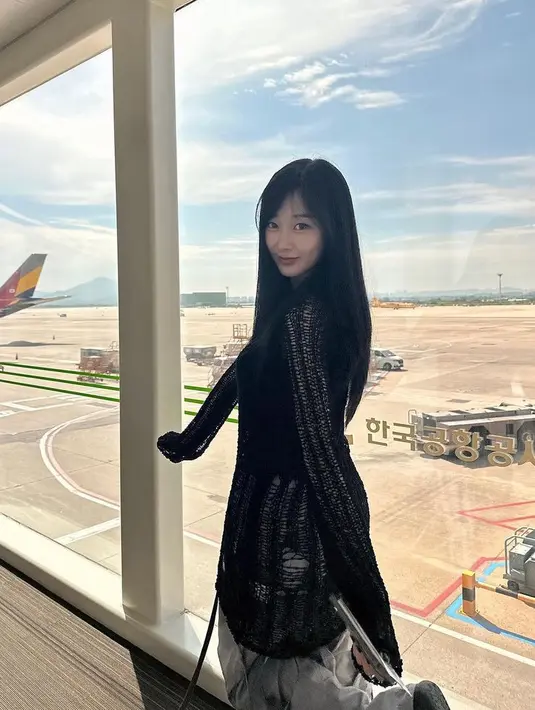 Giselle tampil dengan atasan hitam lengan panjang dipadukan celana panjang abu-abu cocok untuk gaya fashion airport.  [@aerichandesu]
