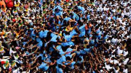 Pemuda India membentuk piramida manusia untuk memecahkan pot berisikan semacam susu dalam perayaan Festival Janmashtami di Mumbai, Senin (3/9). Para remaja mendaki ke tingkat paling atas tanpa alat keamanan sama sekali. (AP/Rafiq Maqbool)