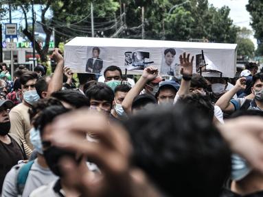 Pencari suaka membawa replika peti jenazah saat unjuk rasa di depan kantor UNHCR, Jakarta, Senin (14/12/2020). Mereka meminta agar proses perpindahan ke negara tujuan dipercepat setelah adanya tiga orang pengungsi yang bunuh diri dalam dua minggu terakhir karena depresi. (merdeka.com/Iqbal Nugroho)