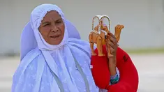 Seorang jemaah haji membawa mainan saat tiba di Bandara Internasional Sultan Iskandar Muda, Blang Bintang, Aceh, Senin (31/7/2023). Sebanyak 254 jemaah haji Aceh yang tergabung dalam kelompok terbang (kloter) 12 atau kloter terakhir sudah di tiba di Aceh pada siang ini. (Chaideer MAHYUDDIN/AFP)
