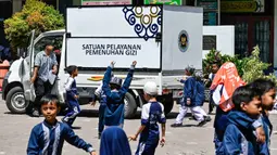 Truk makanan dari program Makan Bergizi Gratis (MBG) terlihat melewati para siswa di sebuah sekolah dasar di Banda Aceh pada Kamis 30 Oktober 2025. Makanan yang sudah disiapkan di dapur SPPG diantar langsung ke sekolah-sekolah dan lokasi penerima. (CHAIDEER MAHYUDDIN/AFP)
